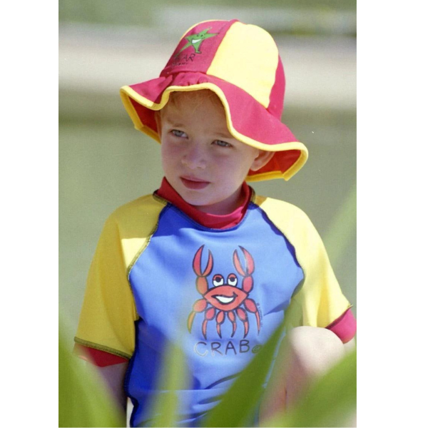 A little boy wearing our Ozi Varmints Lycra Swim Panel Hat Red/Sun